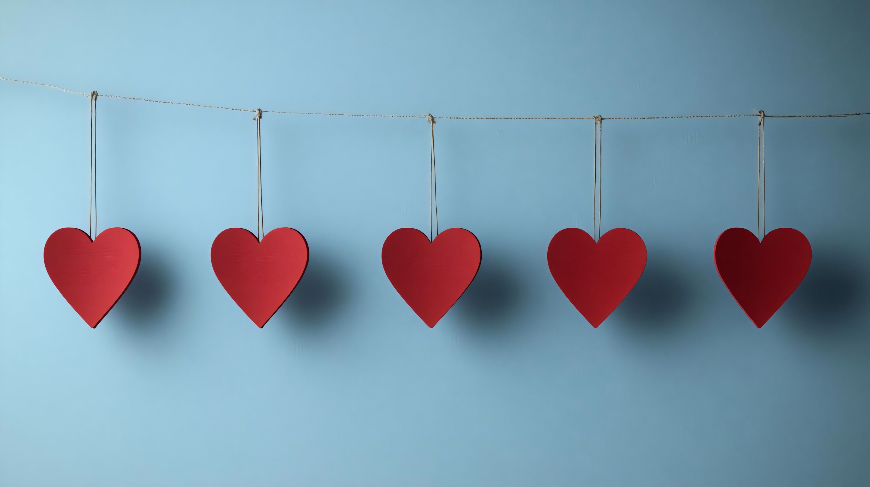red heart decorations hanging on string with blue background