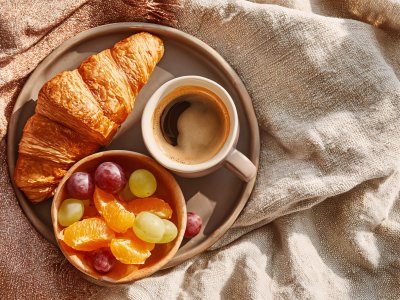 cozy breakfast with croissant, coffee, and fresh fruits on plate